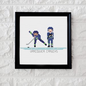 Op de afbeelding: Borduurpatroon met twee Vancouver Canucks-hockey spelers in hun blauw-groene uniformen. De tekst "Vancouver Canucks" staat onder de spelers.