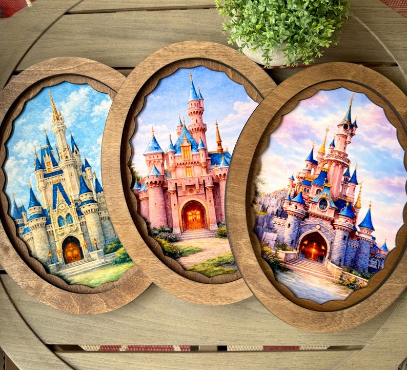 May include: Three wooden framed art pieces featuring watercolor paintings of fairytale castles. Each castle has a unique design with blue and pink turrets, set against a blue sky. The frames have a scalloped edge.