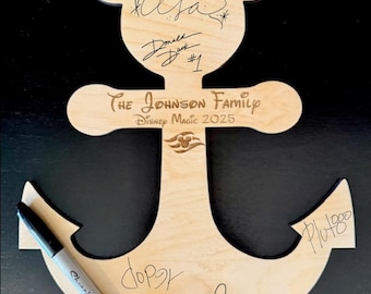 May include: Wooden anchor-shaped sign with a Mickey Mouse head design at the top. The sign features signatures of Disney characters and the text "THE JOHNSON FAMILY DISNEY MAGIC 2025". A black marker rests on the sign.