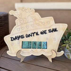 May include: A wooden ship-shaped countdown clock with the text "DAYS UNTIL WE SAIL." The clock displays the time remaining: 37 days, 14 hours, 18 minutes, and 39 seconds. The design includes Mickey Mouse silhouettes.