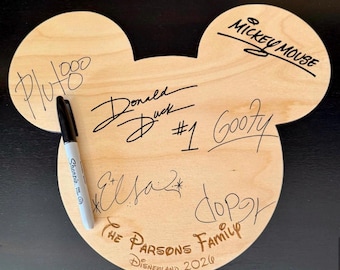 May include: A wooden Mickey Mouse head-shaped sign with signatures of Disney characters Pluto, Donald Duck, Goofy, and Elsa. The sign also includes the text "The Parsons Family Disneyland 2020" and a black Sharpie marker.