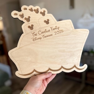 May include: A wooden cutout of a ship with Mickey Mouse ears on the front. The ship is labeled "The Castillo Family Disney Treasure 2025".