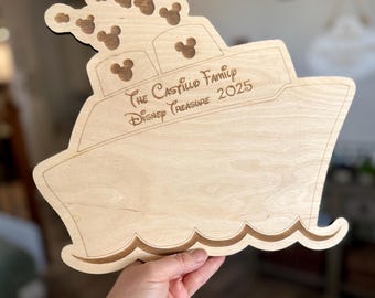 May include: A wooden cutout of a ship with Mickey Mouse ears on the front. The ship is labeled "The Castillo Family Disney Treasure 2025".