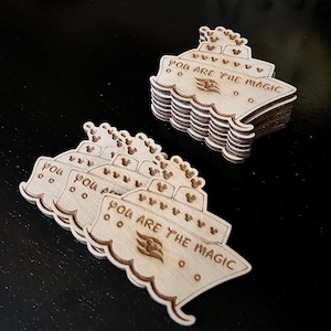 May include: A stack of wooden cruise ship ornaments with the text "You are the magic" and a Disney cruise line logo. The ornaments are decorated with Mickey Mouse heads.