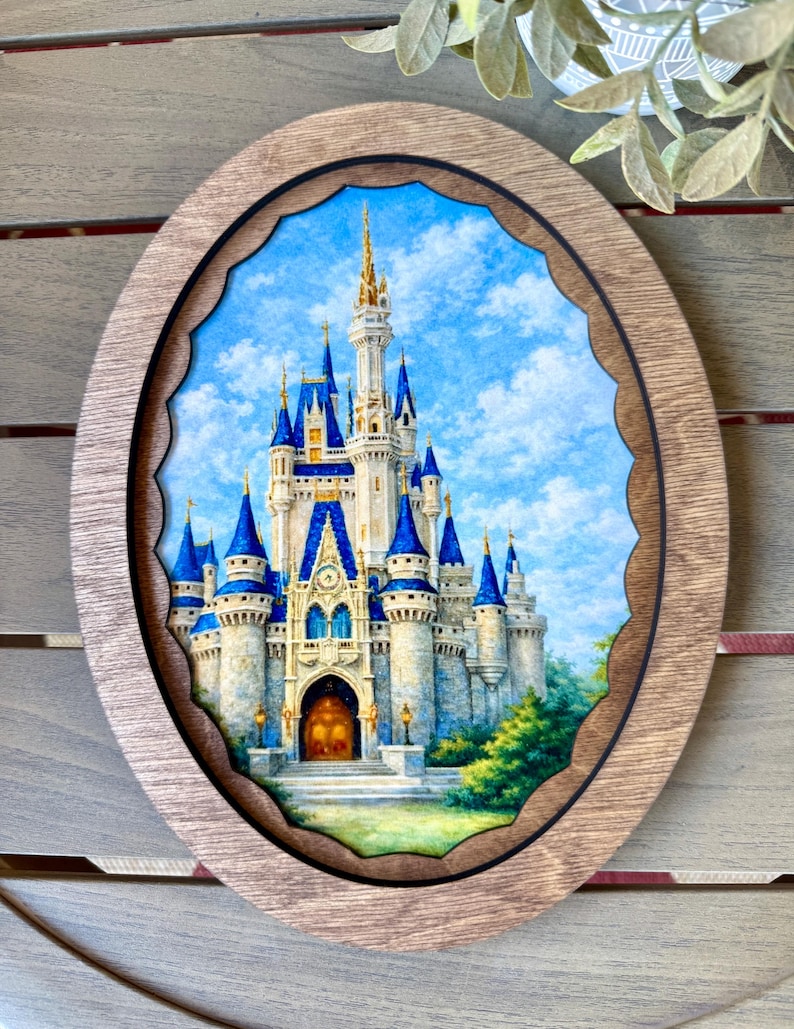 May include: An oval wooden framed artwork featuring a detailed painting of a fairytale castle with blue turrets and a golden spire against a blue sky. The frame has a scalloped inner edge.