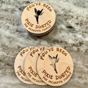 May include: Four wooden round ornaments with the text "You've Been Pixie Dusted The McHaffa Family" and a silhouette of Tinkerbell.