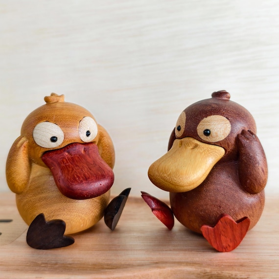 Hand-cut wooden Psyduck & Cubone figures that look like they belong on a gamer's shelf — tactile, charming, and clearly made by an actual human with a scroll saw.