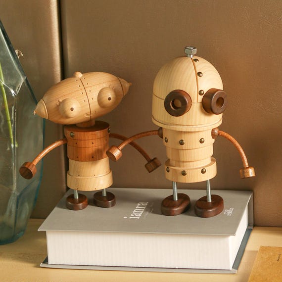 A hand-carved wooden robot straight out of Machinarium — the kind of one-of-a-kind desk sculpture that makes visitors stop and ask 'where did you get that?'