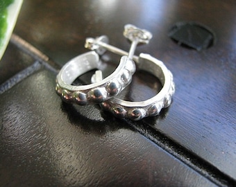 May include: A pair of silver hoop earrings with a textured, beaded design. The earrings are small and delicate.