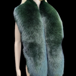 Puede incluir: Una lujosa estola de piel de color verde esmeralda. La estola se muestra sobre un maniquí sobre un fondo negro. La piel tiene un efecto degradado, que pasa de un verde intenso a un tono azul plateado más claro.