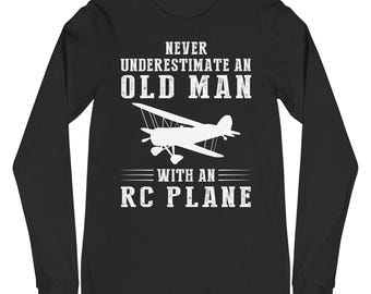 Op de afbeelding: Zwart longsleeve t-shirt met witte tekst die "Never underestimate an old man with an RC plane" luidt. Boven de tekst bevindt zich een wit silhouet van een klein vliegtuig.