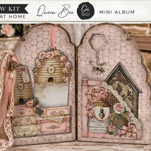 May include: A Queen Bee mini album no sew kit print at home featuring a two-panel folding design with a pink honeycomb background. The album displays illustrations of beehives, bees, roses, lace ribbons, and French text, with scalloped edges.