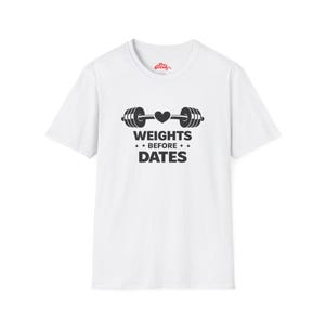 May include: White t-shirt with a black barbell graphic and the text "WEIGHTS BEFORE DATES". The barbell design includes a heart in the center. The shirt is a crew neck style.