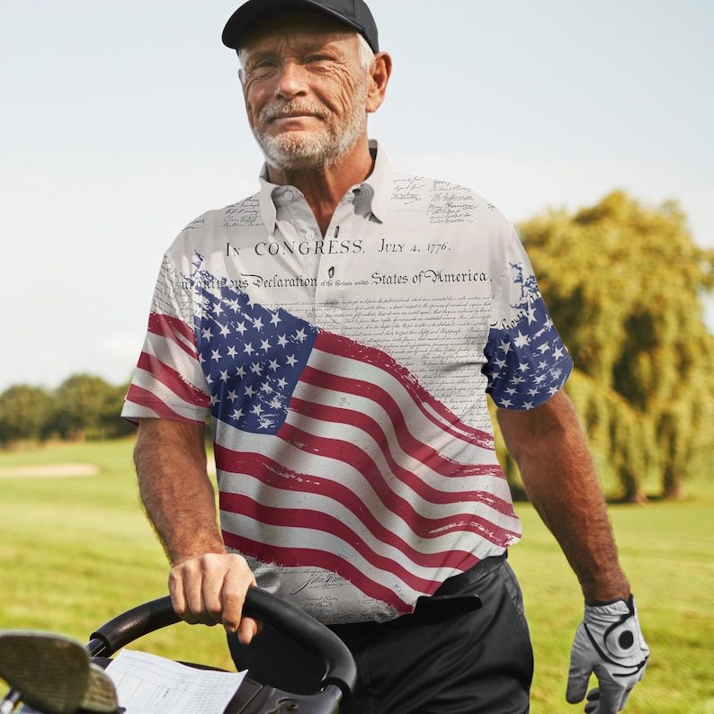 May include: A white polo shirt featuring a distressed American flag design and the text "IN CONGRESS. JULY 4, 1776. Unanimous Declaration States of America."