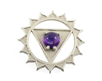 May include: A silver pendant with a purple amethyst stone in the center. The pendant is shaped like a triangle inside a circle with a sunburst design around the outside.