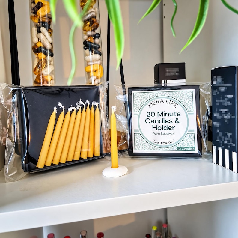 May include: A set of ten yellow beeswax candles in a black box, with one candle standing in a white circular holder. The packaging features the text MERA LIFE 20 Minute Candles & Holder Pure Beeswax TIME FOR YOU 10 Candles on a white label.
