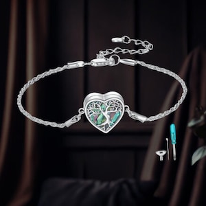 May include: Silver bracelet with a heart-shaped pendant, featuring a tree of life design and iridescent abalone shell inlay. Includes small tools. The bracelet has a delicate chain and a secure clasp. The pendant is approximately 2.5 cm in width.
