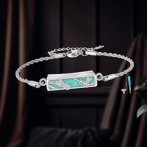 May include: Silver bracelet featuring a rectangular turquoise centerpiece with dragonfly designs. The bracelet has a delicate chain and clasp, with a rope-like texture on the main band. Includes small tools for adjustment.