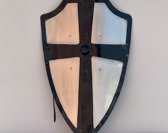 May include: A black and silver shield with a cross design. The shield is made of metal and has a pointed bottom.