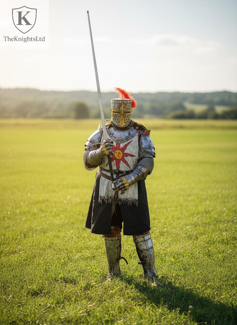May include: A person in full knight armor stands in a grassy field, holding a long sword. The armor is silver and gold, with a red sun emblem on the chest. A red plume adorns the helmet. The KnightsLtd logo is in the upper left.