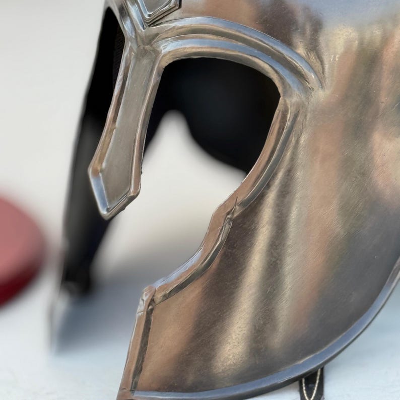 May include: A silver metal helmet with a visor and a textured surface.