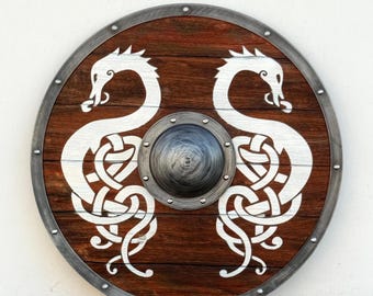 May include: Round wooden shield with a dark brown finish and a silver metal rim. The shield features two white dragon designs with intricate knotwork. A silver metal boss is in the center.