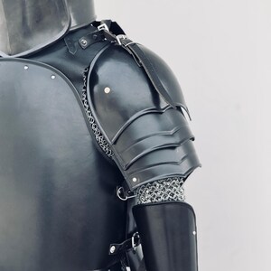 May include: Black leather and metal armor with chainmail. The armor includes a shoulder piece, a chest piece, and a forearm piece.