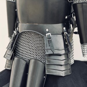 May include: Black leather and metal armor with chainmail. The armor has a segmented design with straps and buckles.