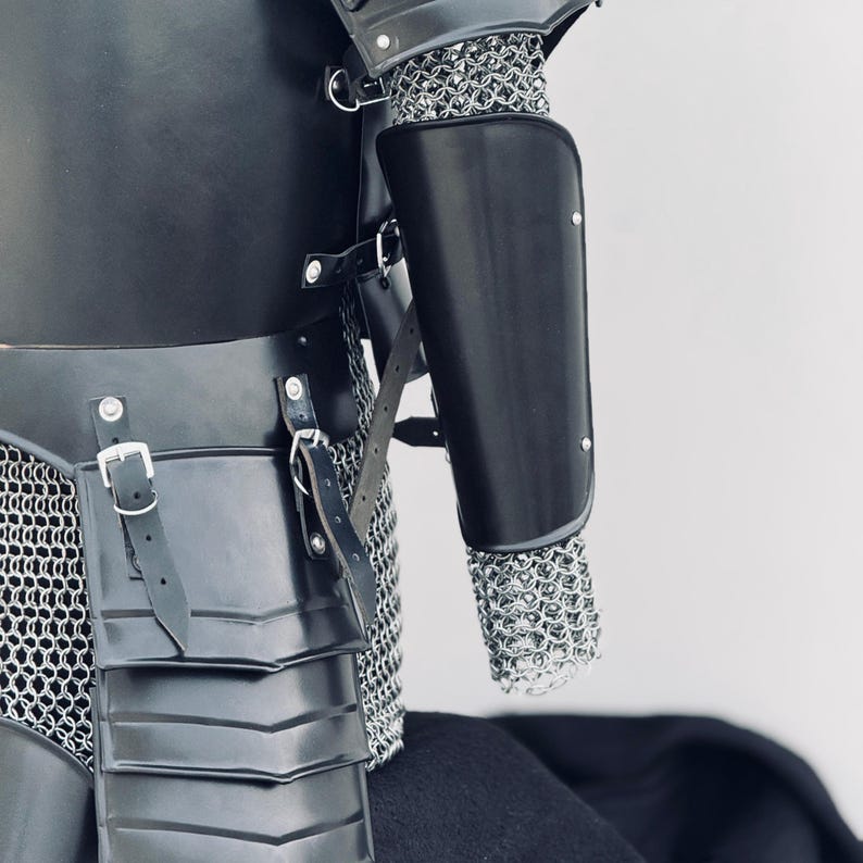 May include: Black leather armor with chainmail and a black leather arm guard. The armor has a belt with a buckle and straps.