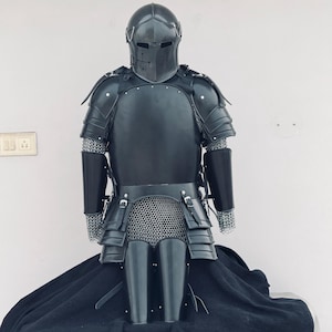 Könnte beinhalten: Schwarze Vollkörperrüstung aus Leder mit Kettenhemd und Helm. Die Rüstung umfasst einen Brustpanzer, Schulterpolster, Handschuhe und Beinschienen.
