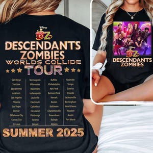 Puede incluir: Camiseta negra con texto dorado "DESCENDANTS ZOMBIES WORLDS COLLIDE TOUR SUMMER 2025". La camiseta muestra las ciudades de la gira y un gráfico de la película. La camiseta está siendo usada.