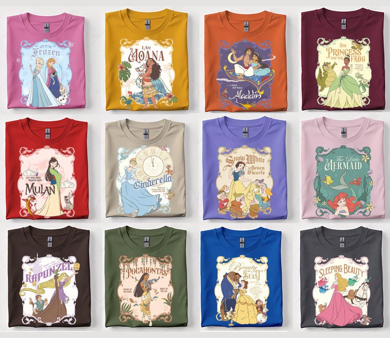 Op de afbeelding: Een verzameling opgevouwen t-shirts met verschillende Disney-prinsessenontwerpen. Elk shirt toont een ander personage of filmtitel, waaronder "Frozen", "Moana", "Aladdin" en "The Princess and the Frog". De shirts zijn in verschillende kleuren, zoals roze, oranje en blauw.
