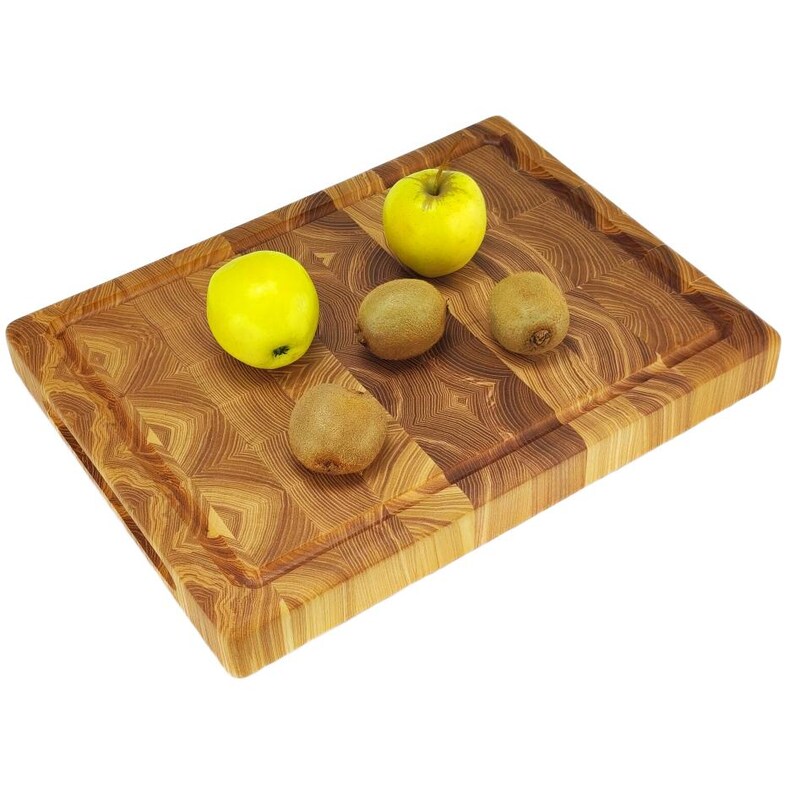 May include: A rectangular wooden chopping board with a light brown finish. Two yellow apples and three kiwis are arranged on the board. The board has a recessed area around the edges.