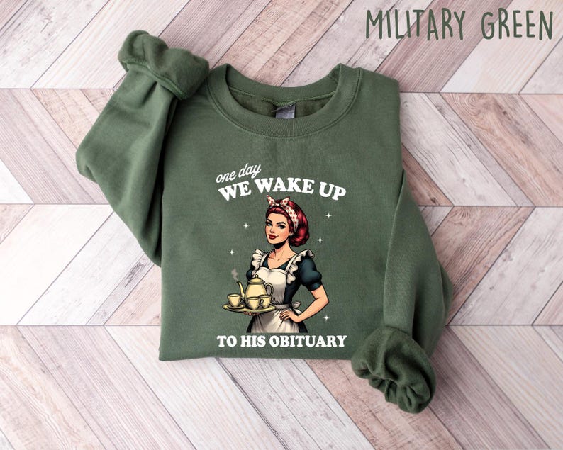 May include: Green sweatshirt with a white graphic of a woman holding a teapot and teacups. The text on the graphic reads "one day we wake up to his obituary".