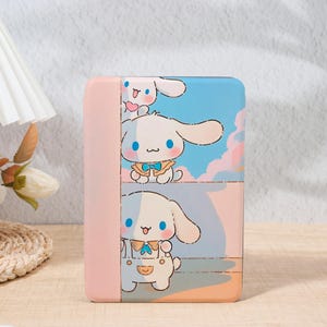 May include: A pink and blue portable charger with a cartoon bunny design. The white bunny has large ears, a blue bow tie, and overalls. The background features a sky and cloud design.