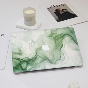 Può includere: Pelle per laptop in marmo verde con sfondo bianco. La pelle ha un motivo a spirale di verde e bianco.