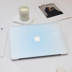 May include: A light blue laptop computer with a white Apple logo on the lid. The laptop is on a white surface.