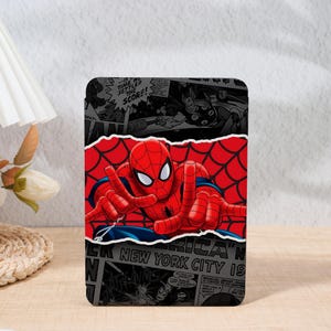 May include: A rectangular Spider-Man themed item featuring a vibrant red Spider-Man graphic against a red spiderweb background. The design incorporates comic book panels in black and white, with text that reads "NEW YORK CITY 19".