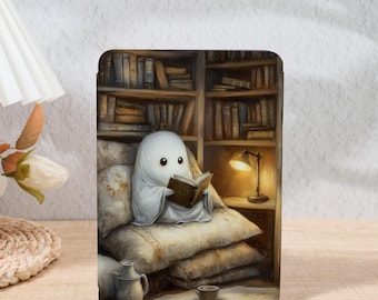 Peut inclure: Illustration d'un fantôme lisant un livre dans une bibliothèque chaleureuse. Le fantôme est assis sur des coussins, avec une lampe et une tasse de café à proximité. L'œuvre d'art a une palette de couleurs douces, créant une atmosphère chaleureuse.