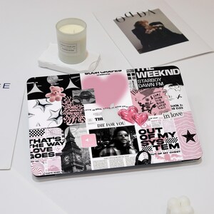 May include: A black laptop with a pink and black collage of stickers. The stickers feature text like "The Weeknd", "Starboy", "Dawn FM", "Die For You", "Out of My System", and "Love is Sour".