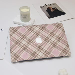 May include: A pink and brown plaid laptop skin with the Apple logo in the center.