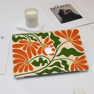 May include: A laptop skin with a floral design featuring orange and green flowers on a cream background.