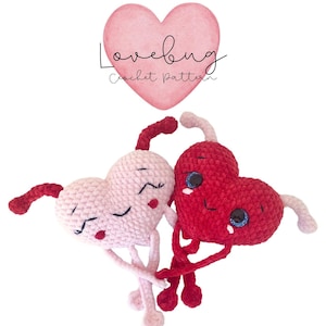 May include: Two crocheted heart-shaped amigurumi toys holding hands. The heart on the left is pink and the heart on the right is red. Both hearts have embroidered eyes and mouths. The text "Lovebug Crochet Pattern" is above the hearts.