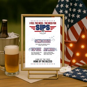 May include: A gold-framed cocktail bar sign with the text "I FEEL THE NEED - THE NEED FOR SIPS." The sign lists cocktail names like "Sonic Booze" and "Jet Mule." An American flag and a star-shaped light are in the background.