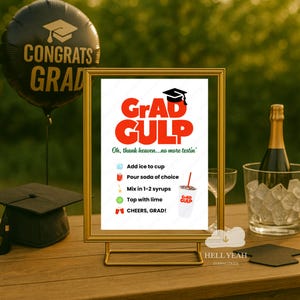 Puede incluir: Una escena de celebración de graduación con un letrero dorado que muestra las instrucciones de "Grad Gulp", un birrete y un globo de "Congrats Grad". Una botella de champán está en una cubitera.
