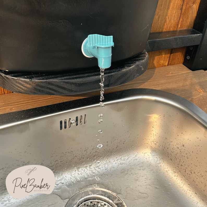 May include: A black water dispenser with a teal spigot, dispensing water into a stainless steel sink. The image includes the text "Pixel Barber Werkstatt".