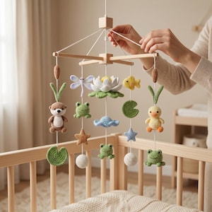 Pode incluir: Móvel de bebê de madeira feito à mão com brinquedos de crochê com tema aquático. O móvel inclui uma libélula, um nenúfar, um peixe, um sapo, um pato, uma estrela do mar e uma criatura marinha. Os brinquedos são de várias cores.