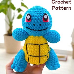 May include: A crocheted blue and yellow turtle plushie with black outlines on the shell. The plushie has white eyes with red accents and a smiling face. The text "Crochet Pattern" is displayed in the upper right corner.