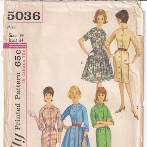 May include: A vintage sewing pattern for a dress, featuring five different styles. The pattern is for size 14, bust 34. The pattern is printed on a white background with pink and black text. The text on the pattern reads "Simplicity Printed Pattern 65c, In Canada 75c".
