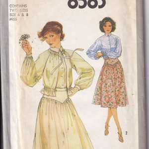 May include: Simplicity sewing pattern number 8583 for a blouse and skirt. The pattern includes two sizes, 6 and 8, for misses. The illustration shows a woman wearing a white blouse with a ruffled collar and a yellow skirt with a gathered waist. The second illustration shows a woman wearing a blue blouse with a white collar and a floral print skirt.